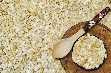 Plate of filled with pumpkin seeds stands on pumpkin seedsの写真素材