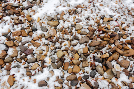 large and small pebbles covered with snowの写真素材