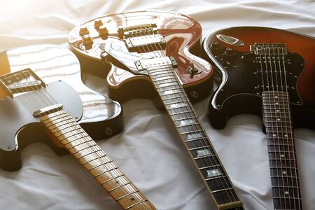 Three electric guitars placed on a white cloth, for sing a song, macro abstract         の写真素材