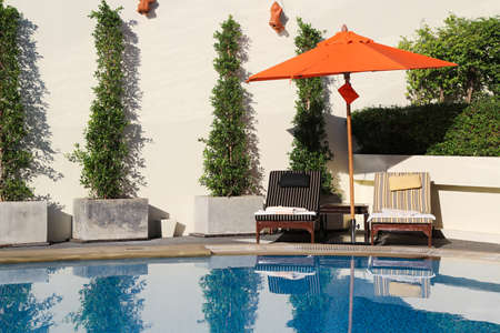 Lounge chairs with umbrella in a swimming pool invite you to relax のeditorial素材