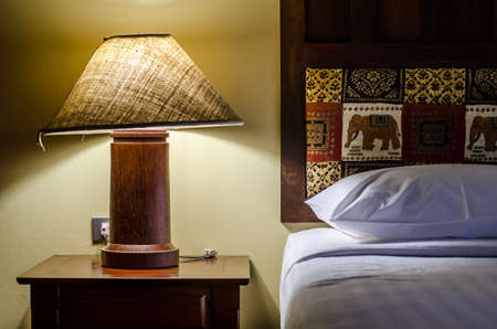 shining lamp on the table near bed in hotelの写真素材