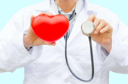 A doctor with stethoscope and red heart in hand, isolated on blueの写真素材