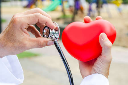 Doctor with stethoscope examining red heartの写真素材