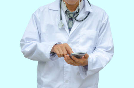 Doctor hands texting on a smart phone isolated on a blue backgroundの写真素材