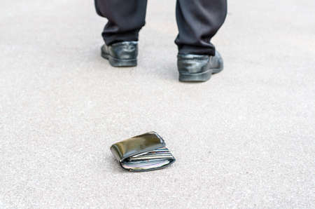 Lost wallet on the street in the park and legs of the walking man conceptの写真素材