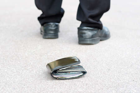 Lost wallet on the street in the park and legs of the walking man conceptの写真素材