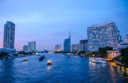 Bangkok cityscape with river and boat at night time . Chao Phraya river scene in Bangkok City, Thailand,cityscape , focus is buildingの写真素材