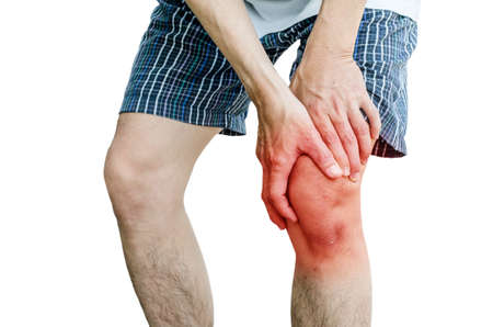 Acute pain in a man knee. male holding hand to spot of knee-aches. Isolation on a white background.の写真素材