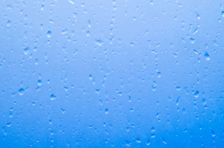 Water droplets on the glass with a colored background. Drops of water.