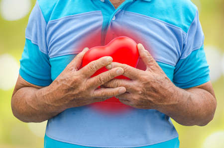 Old man holding heart because of heart infarctionの写真素材