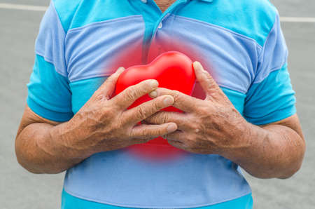 Old man holding heart because of heart infarctionの写真素材