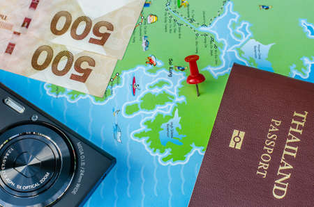 Black compact camera and map and money and passport on wood tableの写真素材