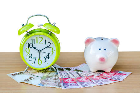 Piggy bank with money and alarm clock on white backgroundの写真素材