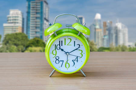 alarm green clock on table with city background.の写真素材