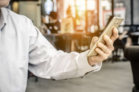 young man working from coffee shop using smart phone , man's hands using smart phone in interior.の写真素材