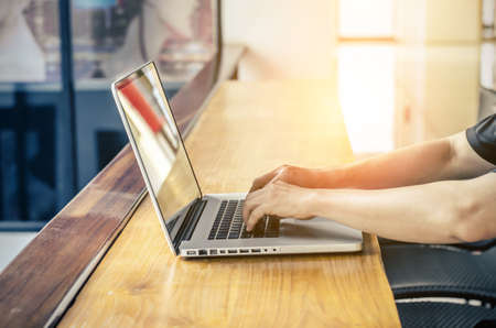 Business man using hands typing in a laptop computer in a coffee shop.の写真素材