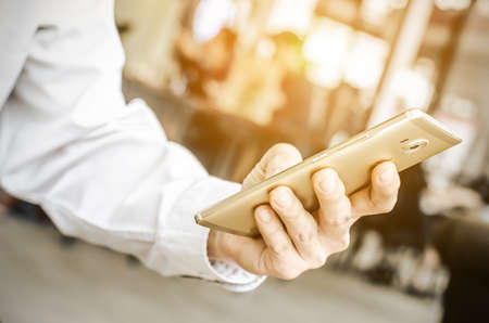young man working from coffee shop using smart phone , man's hands using smart phone in interior.の写真素材