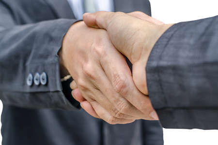 Closeup of two businessmen shaking hands against white backgroundの写真素材