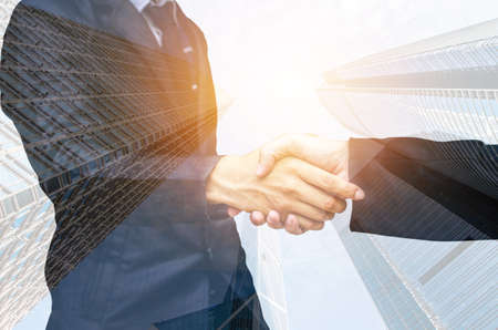 Double exposure of two businessmen shaking hands against white backgroundの写真素材