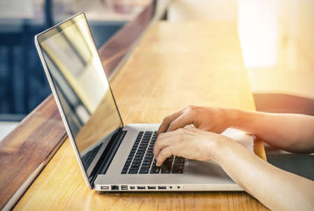 Business man using hands typing in a laptop computer in a coffee shop.の写真素材