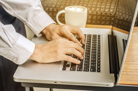 Close up of a man hands typing in a laptop in a coffee shop terrace in the streetの写真素材
