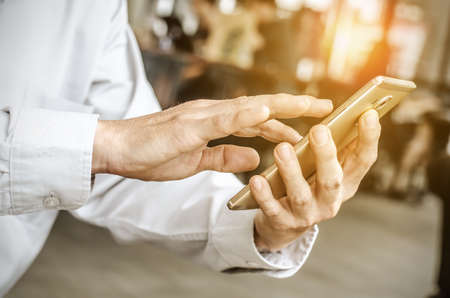 young man working from coffee shop using smart phone , man's hands using smart phone in interior.の写真素材