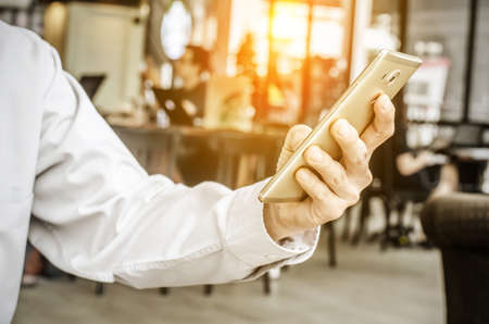 young man working from coffee shop using smart phone , man's hands using smart phone in interior.の写真素材