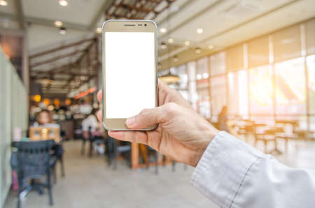 Mockup image of hand holding gold mobile phone with blank white screen and coffee shop 
