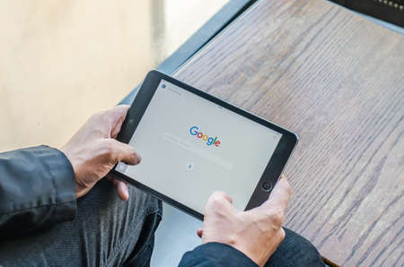BANGKOK, THAILAND - APRIL 18, 2017: Google icons on web browser Ipad smart device touchscreen in businessman hands in relax time: Cyber mobile online wireless wifi technology lifestyle digital 4.0 ageのeditorial素材