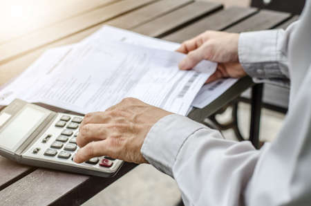 Man using calculator and thinking about cost  with paying billsの写真素材