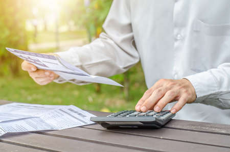 Man using calculator and thinking about cost  with paying billsの写真素材