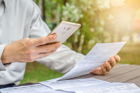 Businessman with bills and smart phone at the table. Calculation of costsの写真素材