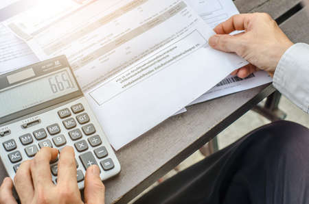 Top view man using calculator and thinking about cost  with paying bills