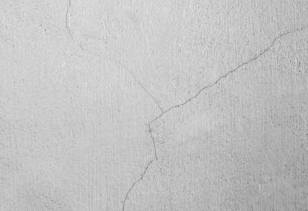 cracked concrete wall covered with gray cement surface as backgroundの写真素材