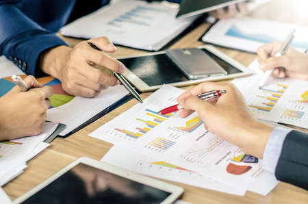 Close-up of business team image of male pen pointing at business document during discussion at meeting and using pen with financial diagram and digital tabletの写真素材