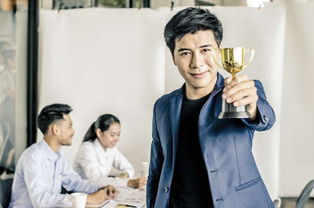 Businessman holding trophy award for success in business, business team happy consent and successful business team rewarded for in the officeの写真素材