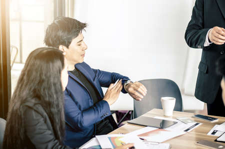 Business, people, time management and office concept - Businessman looking at his watch in meeting at officeの写真素材