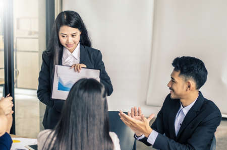 Photo of successful young manager standing making a presentation financial diagram while the others listening to himの写真素材