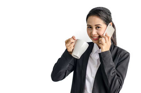 businesswoman using cell phone while holding disposable coffee cup on white backgroundの写真素材