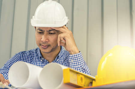 Waiting for inspiration. Asia Engineer serious thinking, young man and looking away while sitting at container box backgroundの写真素材