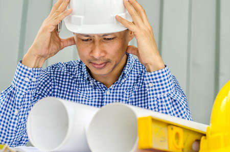 Waiting for inspiration. Asia Engineer serious thinking, young man and looking away while sitting at container box backgroundの写真素材