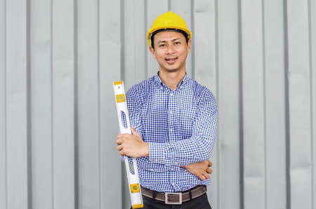 Engineer Man holding level measuring instrument and standing at container box backgroundの写真素材