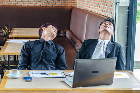 Two Tired Young Businesspeople Sleeping in chair at coffee shopの写真素材