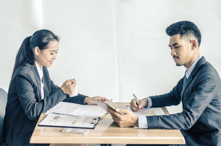 Two confident businesspeople using a digital tablet together while working at a table in a modern officeの写真素材