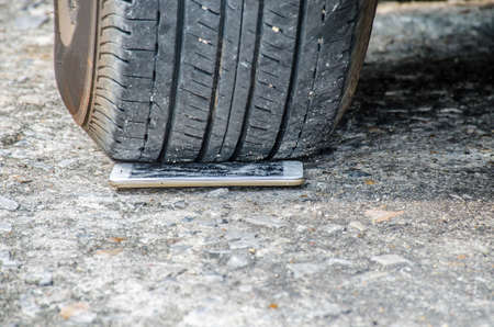 Smartphone display smashed by wheel car on floor road background. Close Up, selective focusの写真素材