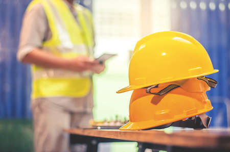 Yellow hard safety helmet hats for safety project of workman as engineer or worker, In the office and working tablet, safety conceptの写真素材