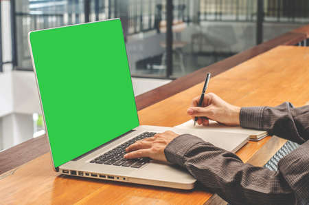 Man with computer, notebook, headset, paper book .business man with copy space for input the text with a green screen on monitor.の写真素材