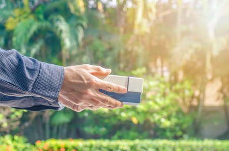 Man hand holding white Gift Box and blue Ribbon on park  Backgroundの写真素材
