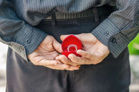 man, groom is holding a box with wedding rings behind his back, wedding concept, happy...