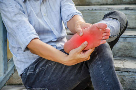 close-up young man feeling pain in his foot because leg cramps and ankles on stair, Have ankle pain, Health conceptの写真素材